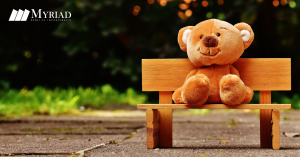 Oso de peluche sentado en una banca de madera