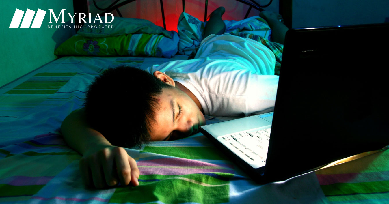 Adolescente dormido en la cama frente a una laptop